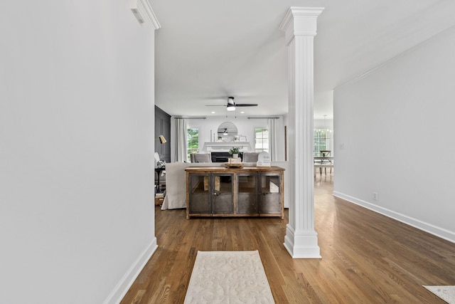 living area with wood finished floors, ceiling fan, baseboards, and decorative columns