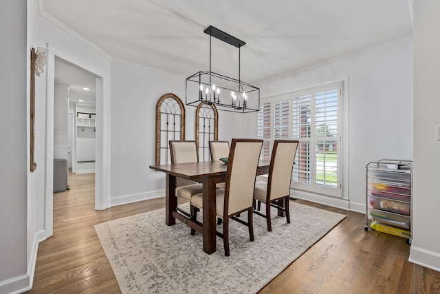 dining area with crown molding, baseboards, a chandelier, and dark wood finished floors