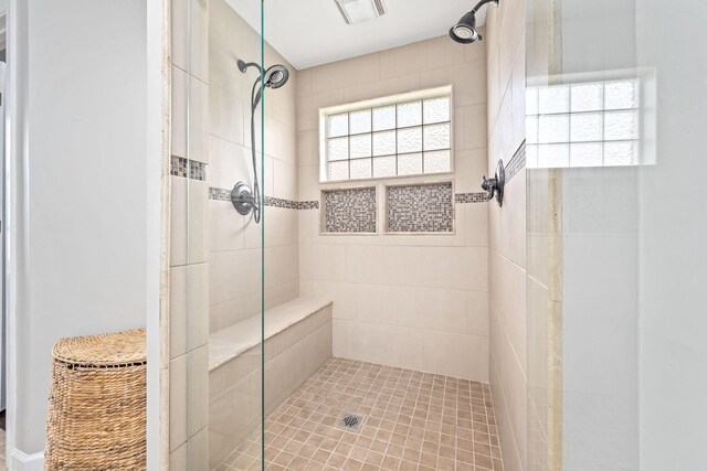 bathroom with a tile shower and visible vents
