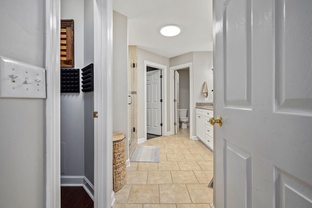 full bath with toilet, a shower stall, vanity, and baseboards