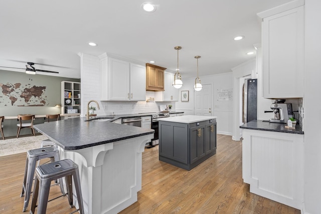 kitchen featuring decorative backsplash, white cabinets, a sink, appliances with stainless steel finishes, and a kitchen island