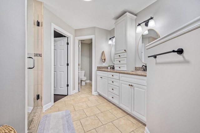 bathroom with a sink, toilet, a stall shower, double vanity, and baseboards