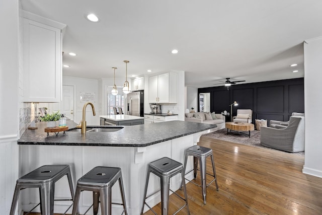 kitchen featuring a sink, stainless steel refrigerator with ice dispenser, a peninsula, and a decorative wall