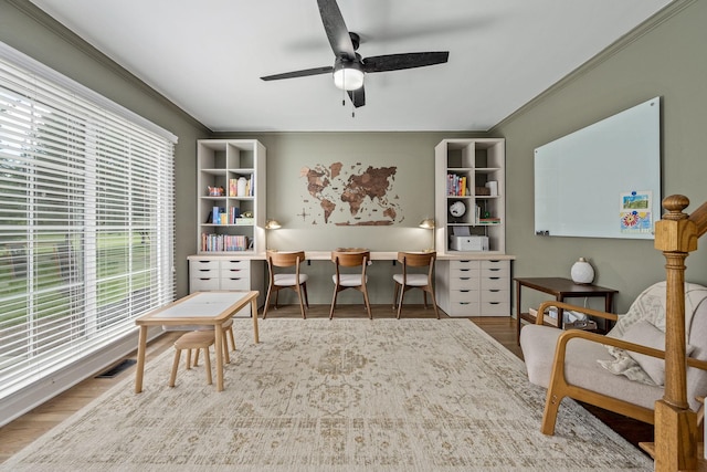 office area featuring a ceiling fan, wood finished floors, a healthy amount of sunlight, and crown molding