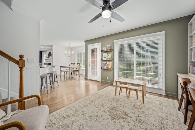 interior space with stairway, wood finished floors, ceiling fan with notable chandelier, and ornamental molding
