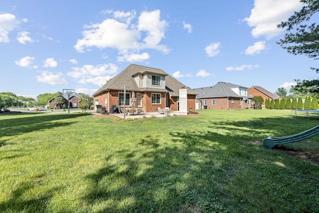 rear view of house with a lawn, a patio area, and brick siding