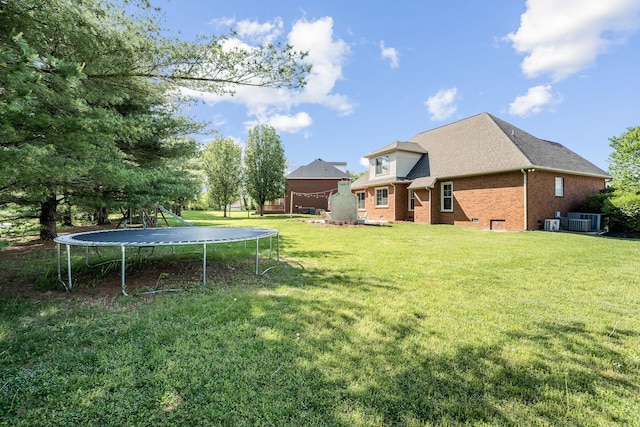 view of yard with central AC and a trampoline