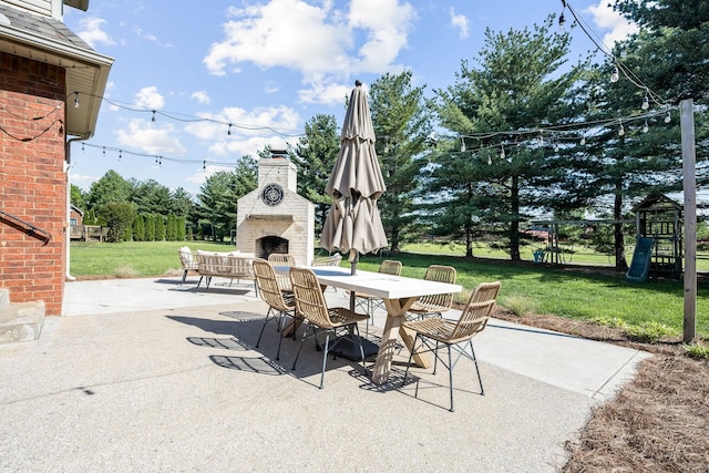 view of patio with outdoor dining space, a playground, and exterior fireplace