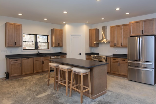 kitchen featuring wall chimney exhaust hood, a sink, dark countertops, recessed lighting, and appliances with stainless steel finishes