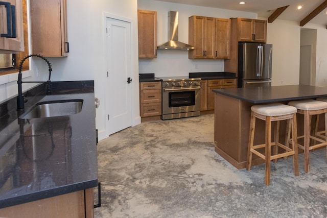 kitchen featuring wall chimney range hood, dark countertops, a sink, a breakfast bar, and stainless steel appliances