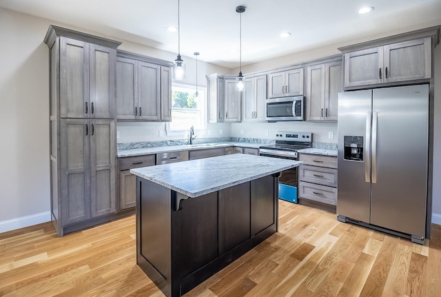kitchen with a kitchen island, light stone countertops, stainless steel appliances, and a sink