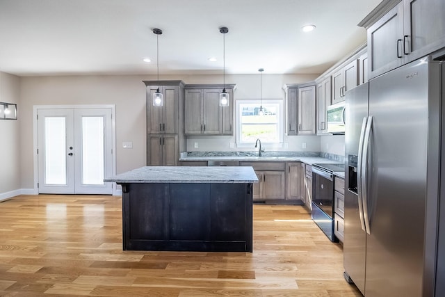 kitchen featuring light wood-style flooring, a kitchen island, hanging light fixtures, and stainless steel appliances