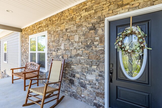 doorway to property featuring stone siding and covered porch