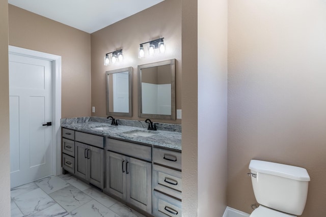 bathroom featuring double vanity, marble finish floor, toilet, and a sink