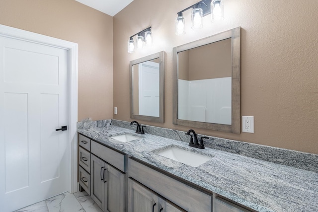 full bath featuring marble finish floor, a sink, and double vanity