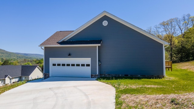 view of side of property with a garage, driveway, and a lawn