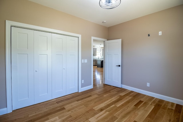 unfurnished bedroom featuring light wood finished floors, baseboards, and a closet