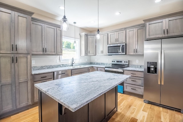 kitchen with a center island, appliances with stainless steel finishes, light stone counters, and a sink