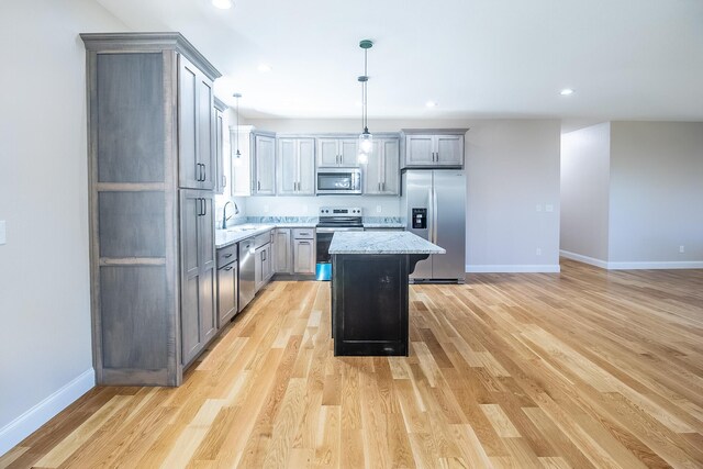 kitchen featuring baseboards, appliances with stainless steel finishes, gray cabinetry, and a sink