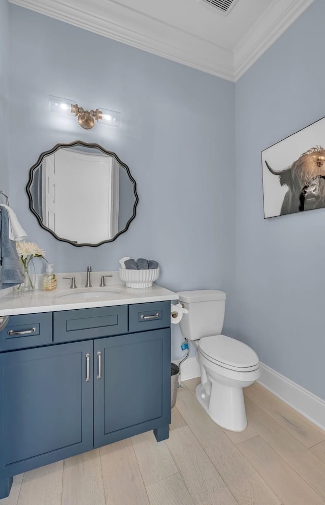 bathroom with toilet, visible vents, baseboards, crown molding, and vanity