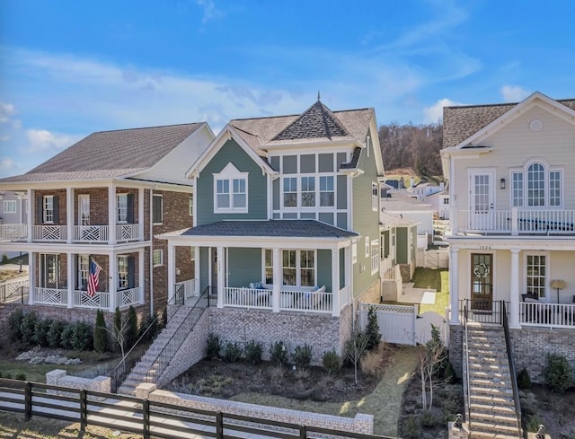 shingle-style home featuring stairway, fence private yard, and covered porch