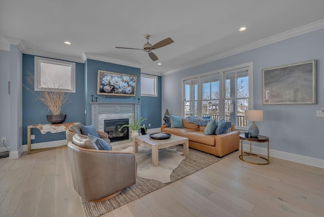 living area with hardwood / wood-style floors, ornamental molding, a glass covered fireplace, and ceiling fan