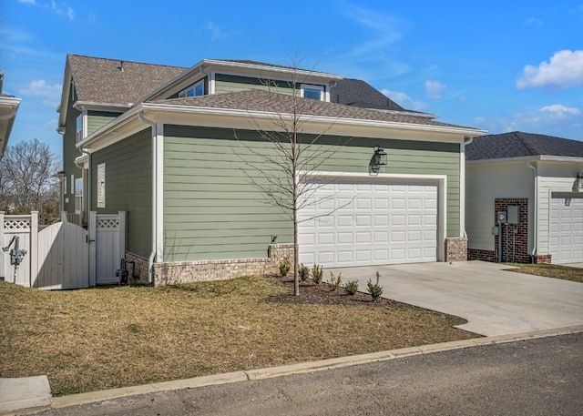 view of home's exterior featuring a lawn, driveway, fence, a garage, and roof with shingles
