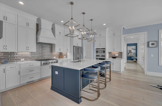 kitchen with a notable chandelier, appliances with stainless steel finishes, light countertops, premium range hood, and white cabinetry