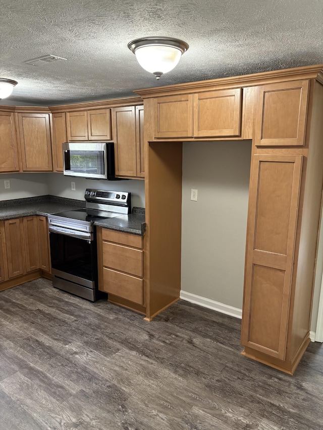 1669 Fellowship Rd, Mount Juliet, TN 37122 - kitchen featuring dark wood-type flooring, dark countertops, appliances with stainless steel finishes, and brown cabinets