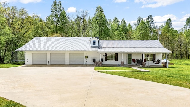 view of front of house featuring concrete driveway, a front lawn, metal roof, covered porch, and a garage