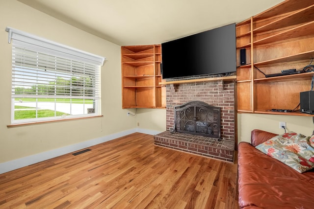 unfurnished living room featuring a fireplace, wood finished floors, visible vents, and baseboards