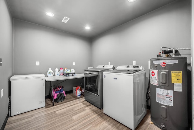 laundry area featuring light wood finished floors, electric water heater, visible vents, and washer and dryer