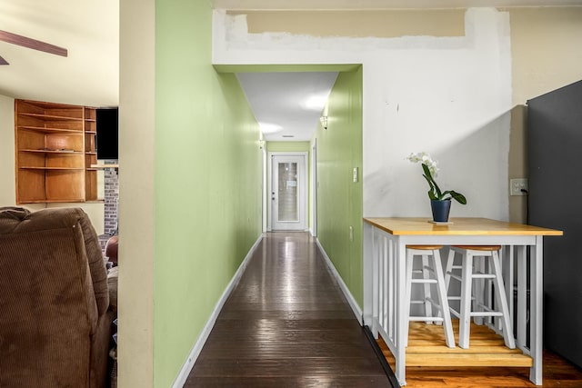 corridor featuring baseboards, built in shelves, and wood-type flooring