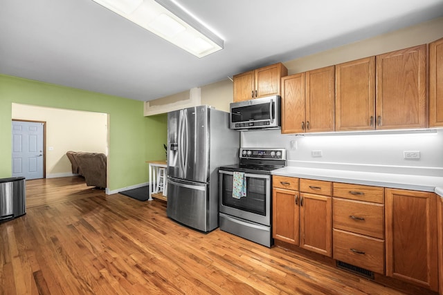 kitchen featuring visible vents, stainless steel appliances, light countertops, and wood finished floors