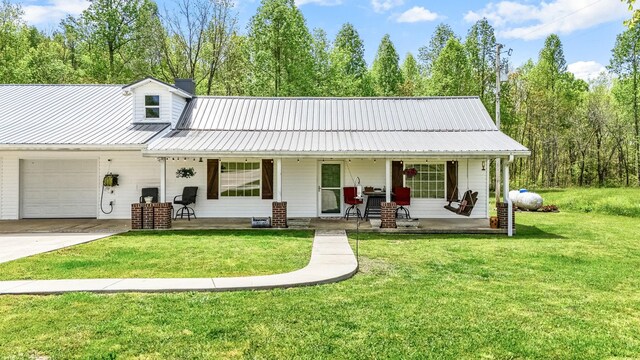 exterior space featuring a front lawn, driveway, metal roof, covered porch, and an attached garage