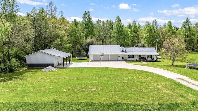 rear view of property featuring a carport, a lawn, a view of trees, and concrete driveway