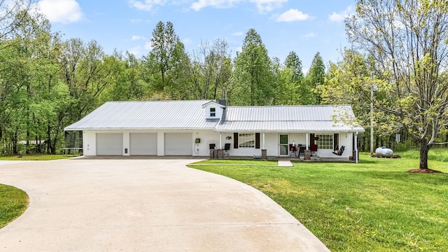 ranch-style home with a front lawn, concrete driveway, an attached garage, a porch, and metal roof