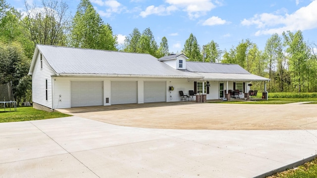 view of front of property with a trampoline, concrete driveway, an attached garage, a porch, and metal roof