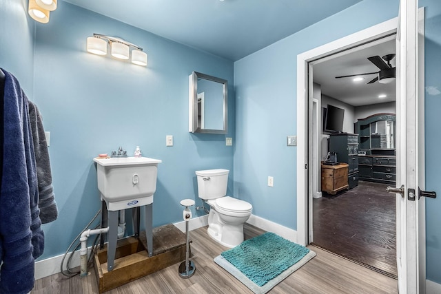 half bath with a ceiling fan, baseboards, toilet, and wood finished floors