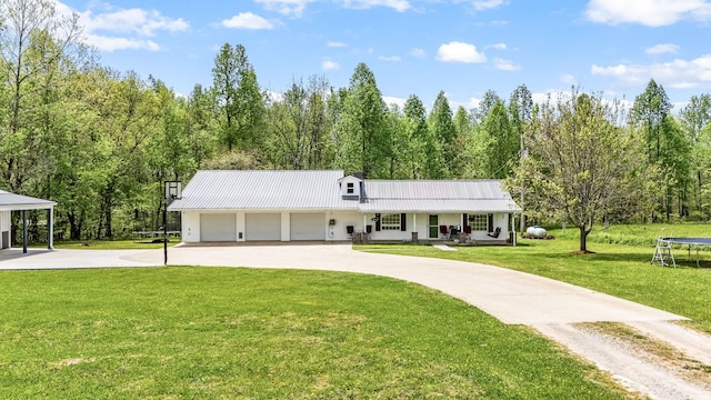 view of front of property featuring a front lawn, curved driveway, a trampoline, covered porch, and metal roof
