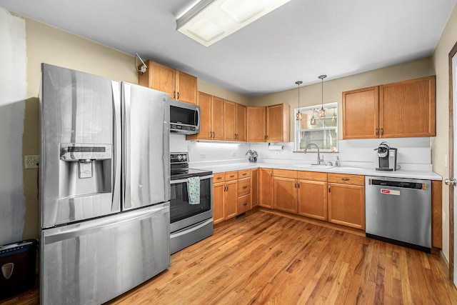 kitchen with light countertops, light wood-style flooring, appliances with stainless steel finishes, and a sink
