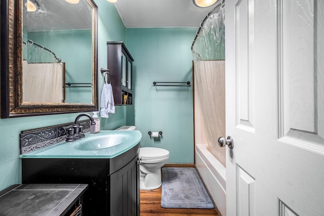 bathroom featuring baseboards, wood finished floors, vanity, and toilet