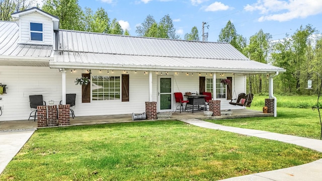 rear view of house with a patio area, a yard, and metal roof