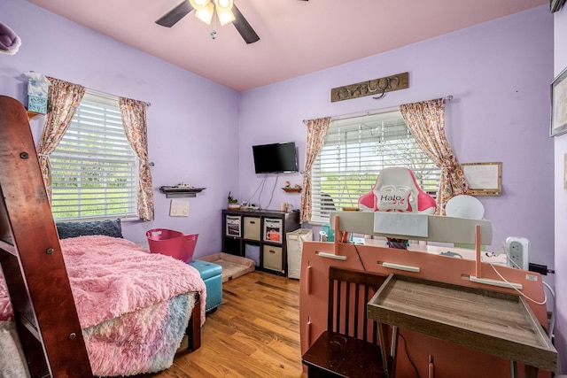 bedroom featuring a ceiling fan, wood finished floors, and multiple windows