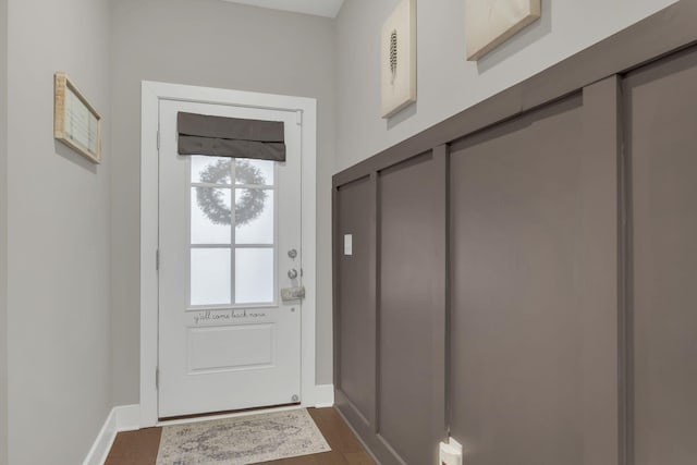 doorway featuring baseboards and dark wood-style floors