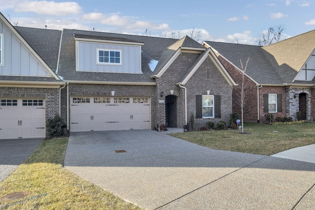 view of front of home with concrete driveway, board and batten siding, an attached garage, a front yard, and brick siding