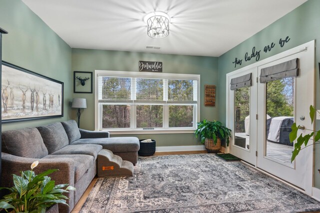 interior space with plenty of natural light, wood finished floors, visible vents, and baseboards
