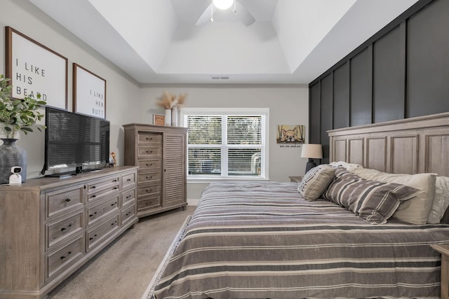 bedroom with a tray ceiling, visible vents, a ceiling fan, and light colored carpet