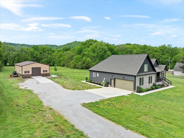 exterior space featuring fence, an outbuilding, a forest view, and a garage