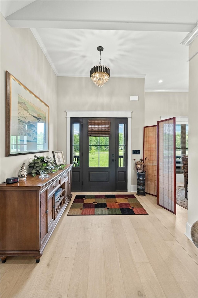 foyer entrance with ornamental molding, a chandelier, and light wood finished floors